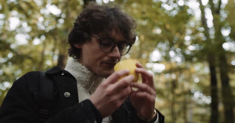 A teenage girl is standing in the woods opening her thermos and she pours a drink and hands it to the guy with her and they each take a drink and walk on the trail