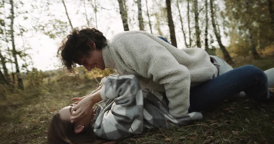 A young couple is being intimate on the ground in the woods