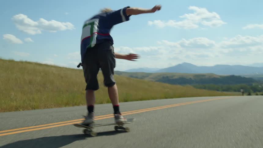 A teenage boy is riding his skateboard down a road and he wipes out after doing a kickflip