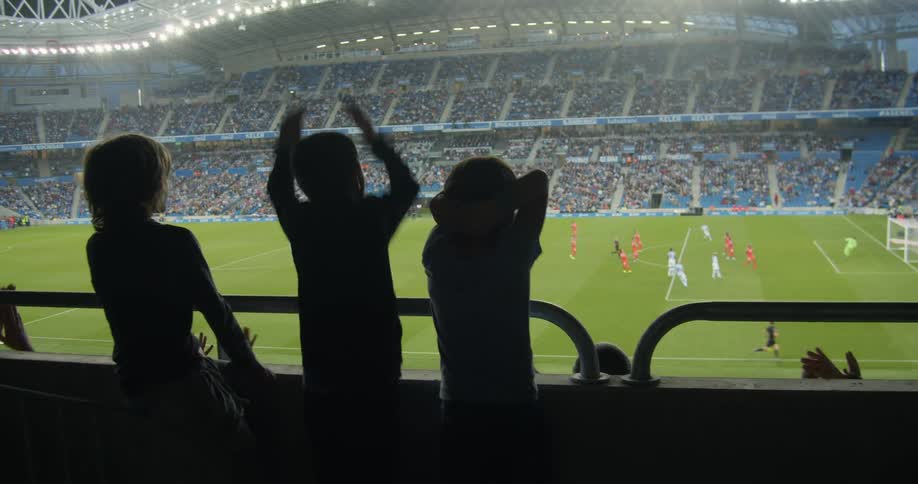 Kids watching and cheering for their team at a soccer stadium