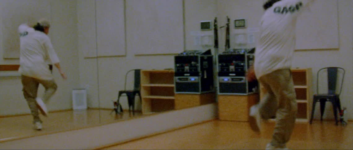 A young man is dancing inside of a dancing studio