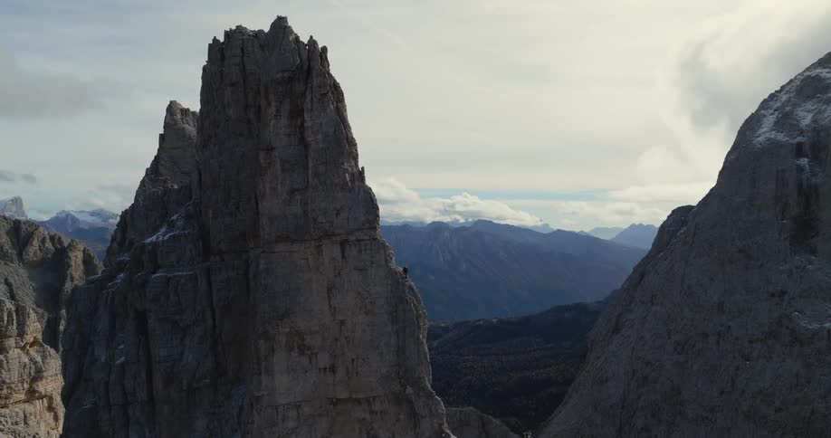 Person climbs steep mountain with forest in misty valley