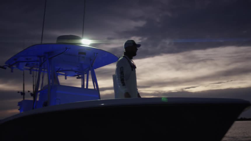 Man standing on a boat sailing on the calm ocean waters at evening