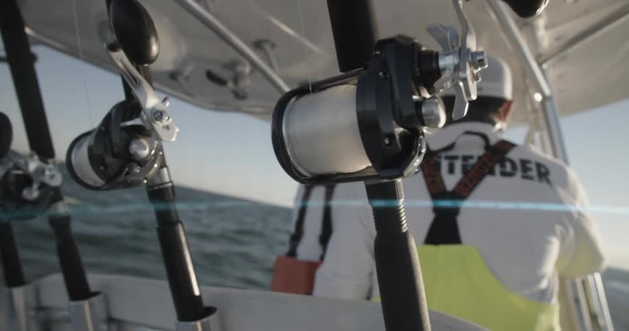 Fishing rods and reels on the back of a boat shake as the boat travels through waves
