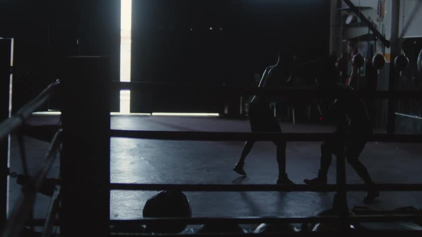 Two people are boxing together in an empty gym