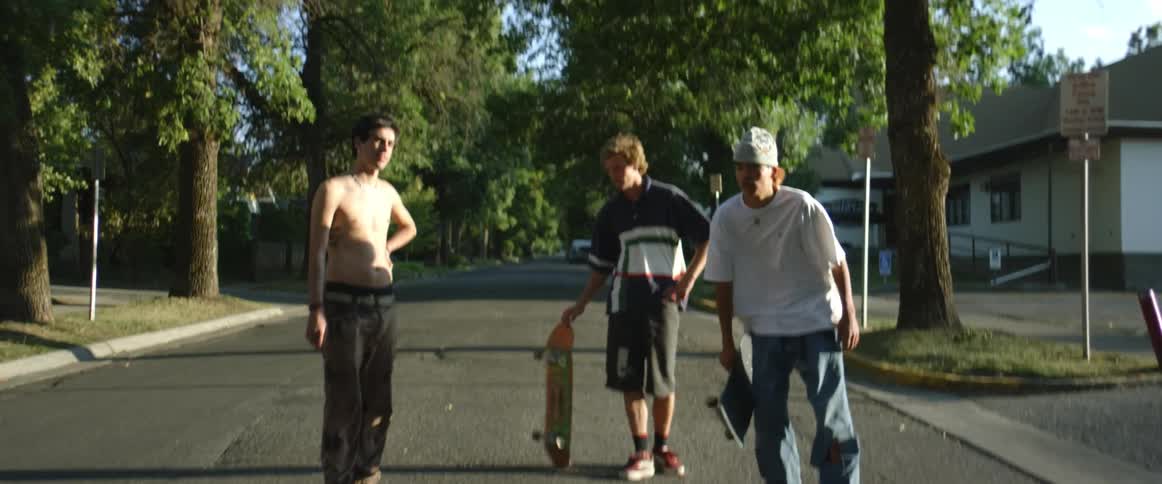 Three teenager boys are standing in the street with there skate boards