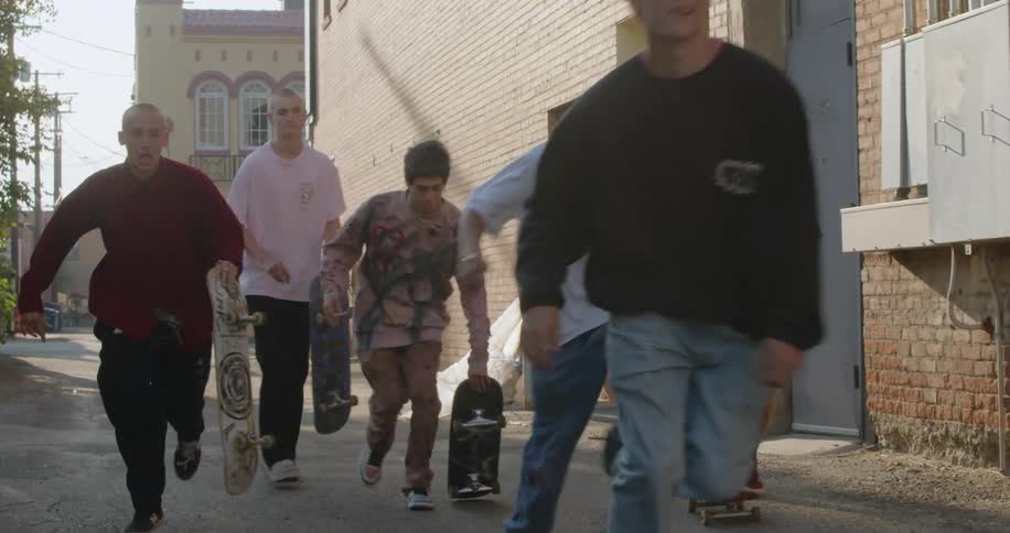 A group of friends are skateboarding in the street around the day time