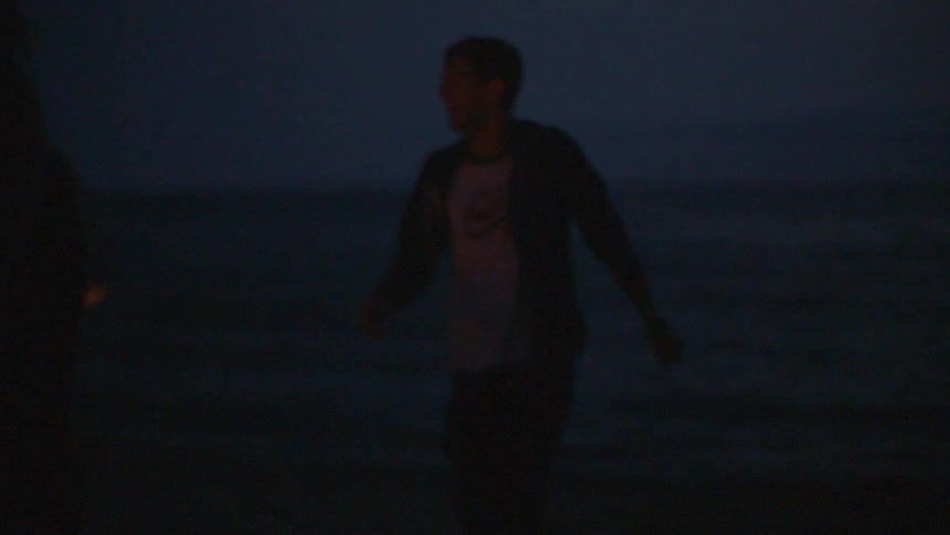 A man throws fireworks on the beach at night