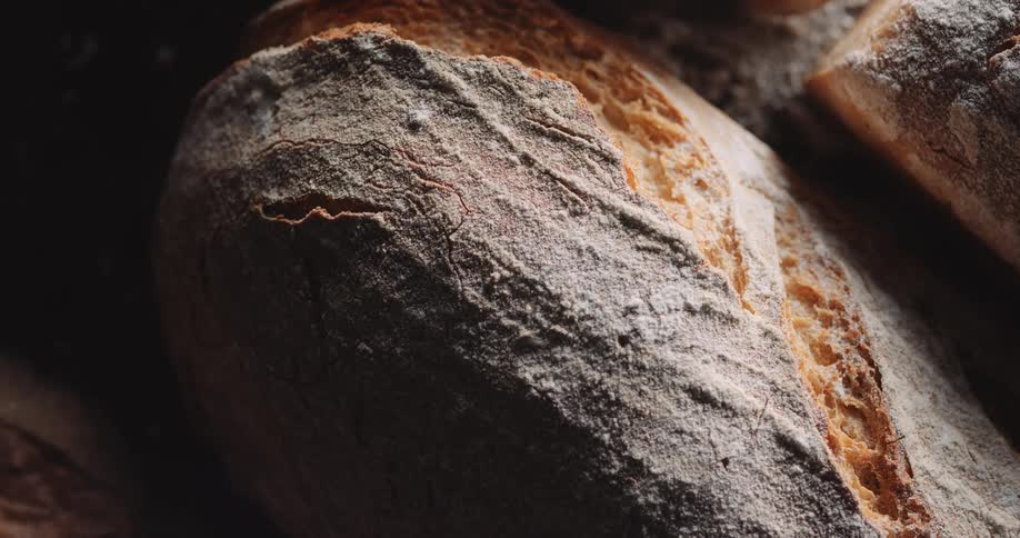 Sunlight brightens on loaves of bread on floured surface before dimming and leaving only darkness