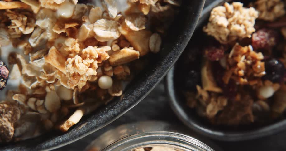 Two bowls of cereal and a jar are shown next to each other on a table