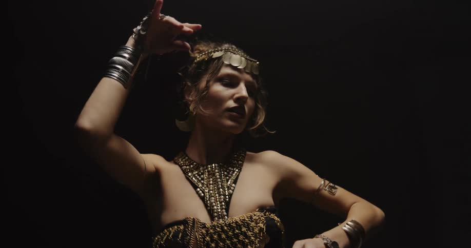 A woman belly dancing in ornate jewelry and costume