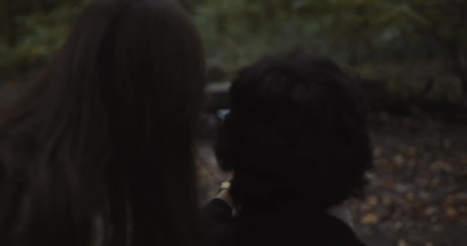 Woman posing for pictures that a man is taking with his phone at the middle of the forest