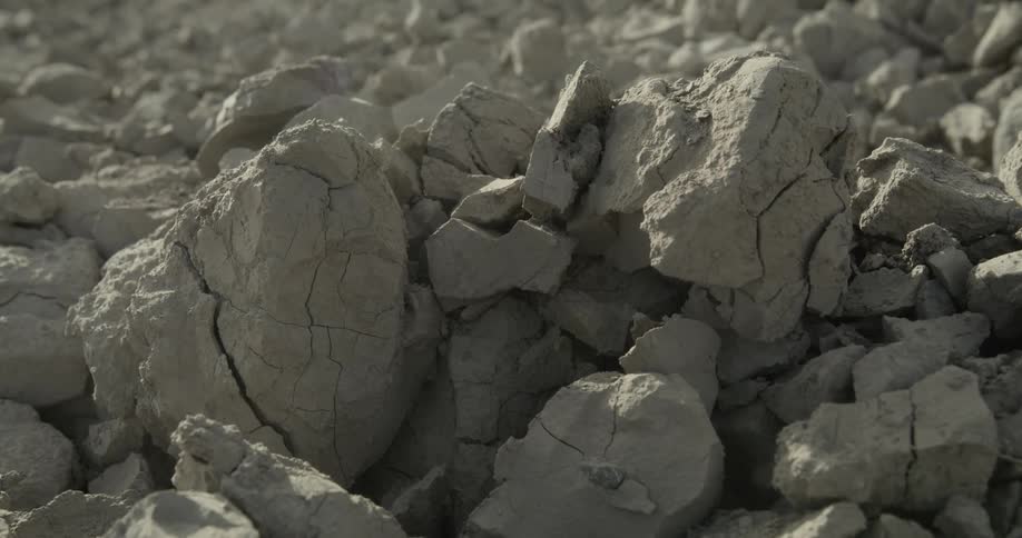 Steam and dust fly up when dirt is tossed on gray cracked rock