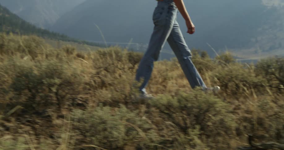 A man walks through tall weeds in a field