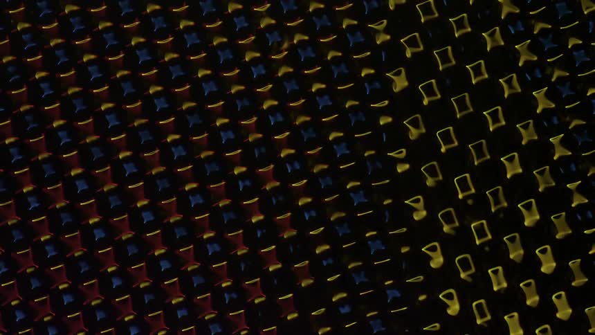 A series of objects on a grid move as they change shape and colors in sync with each other
