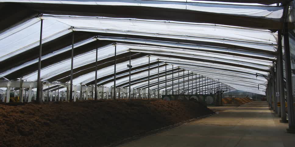 A greenhouse shelter and irrigation over rows of soil