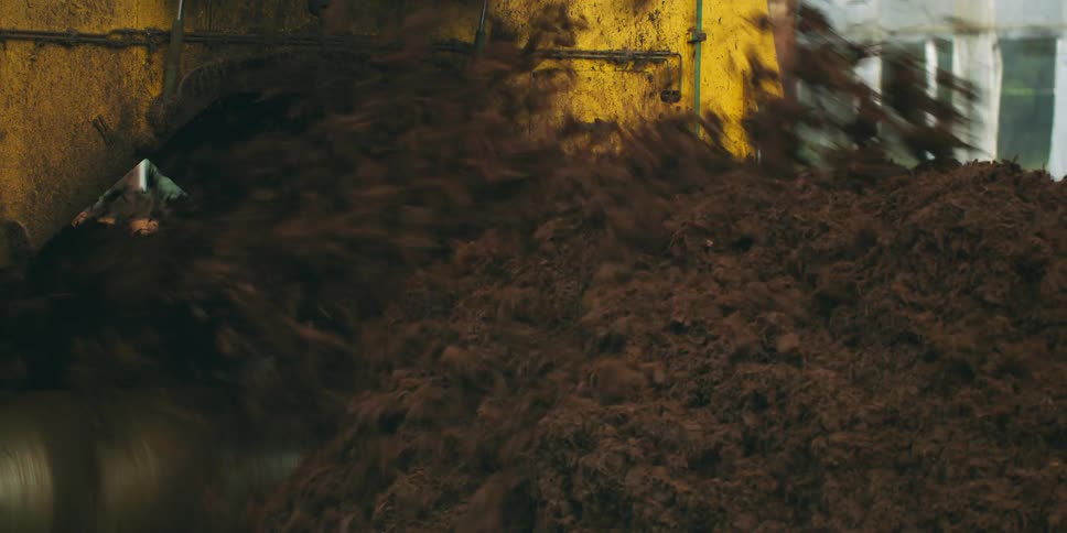 Dirt is flying out from under a machine into a pile near a pavilion