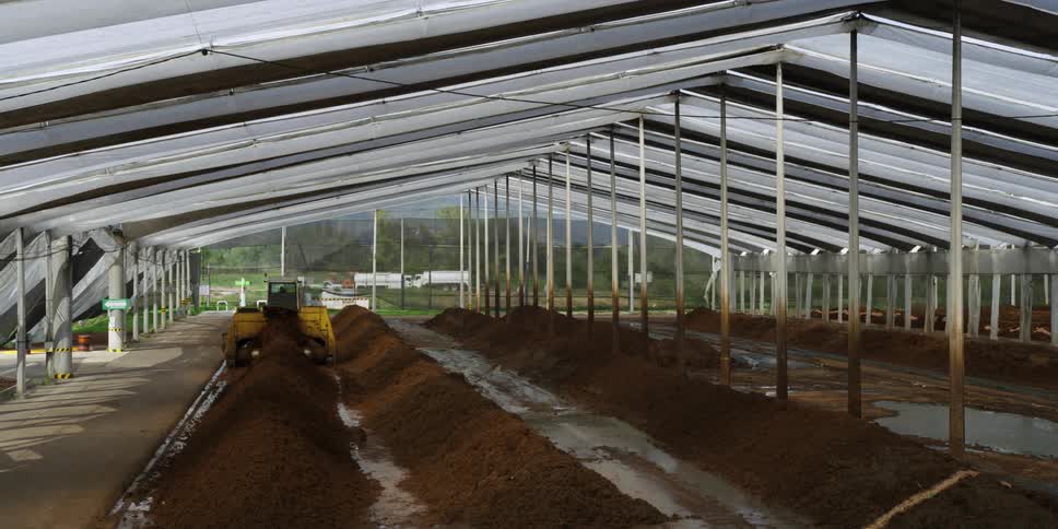 A tractor is used to sift mud in a makeshift building on a farm