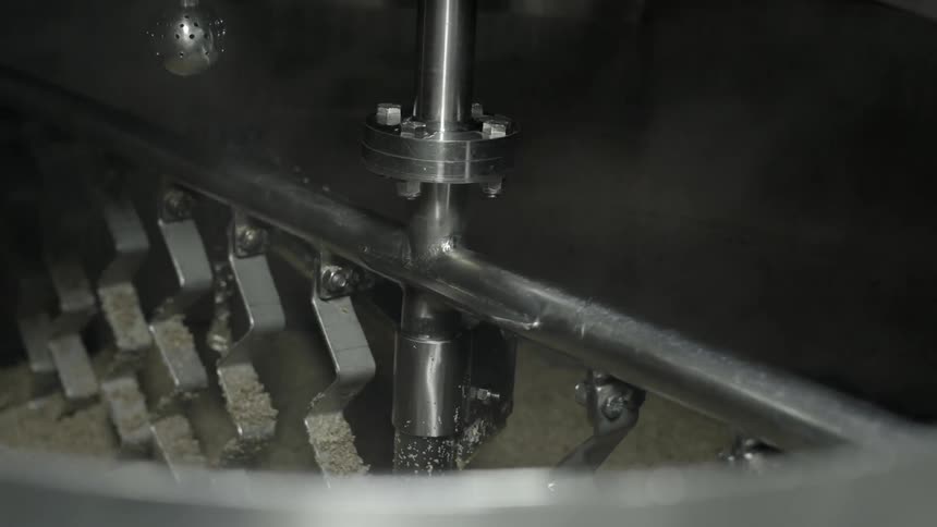 A machine shifts powder in a large mixing bowl