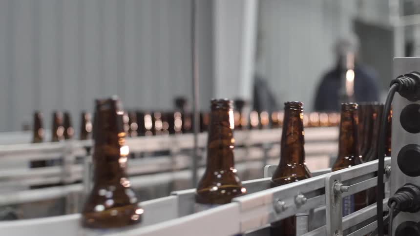Bottles move along a conveyor belt as a man walks over