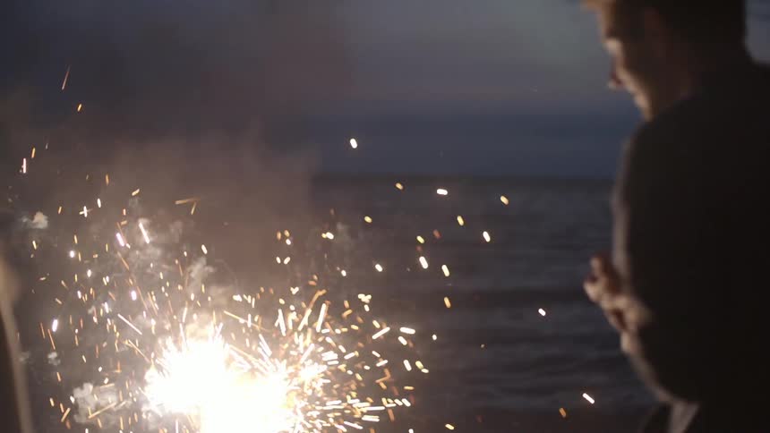 People watch sparklers near a body of water