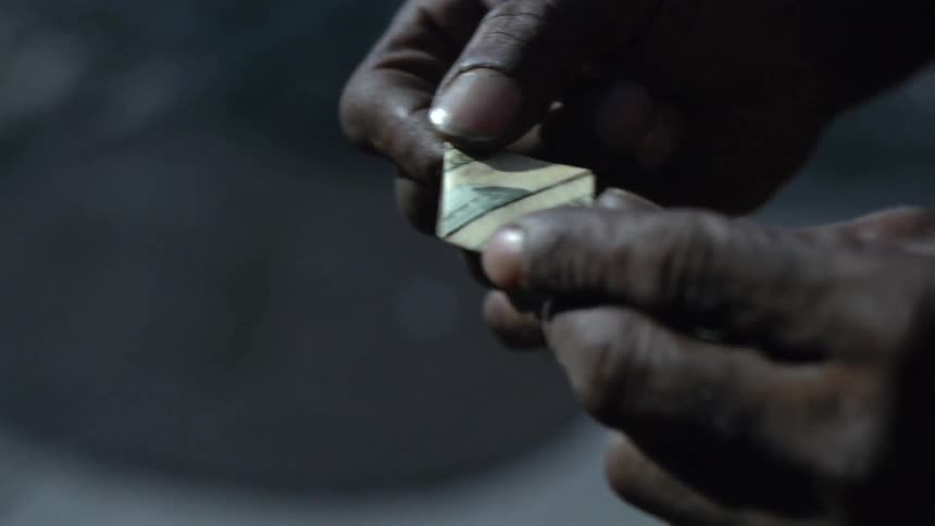 Person holding a ten dollar bill folded into a triangle