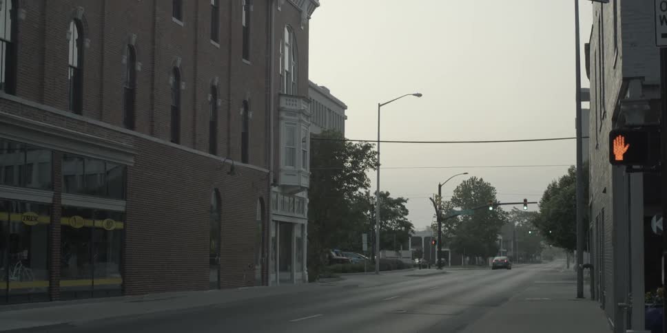 A car travels down an empty city road at dawn