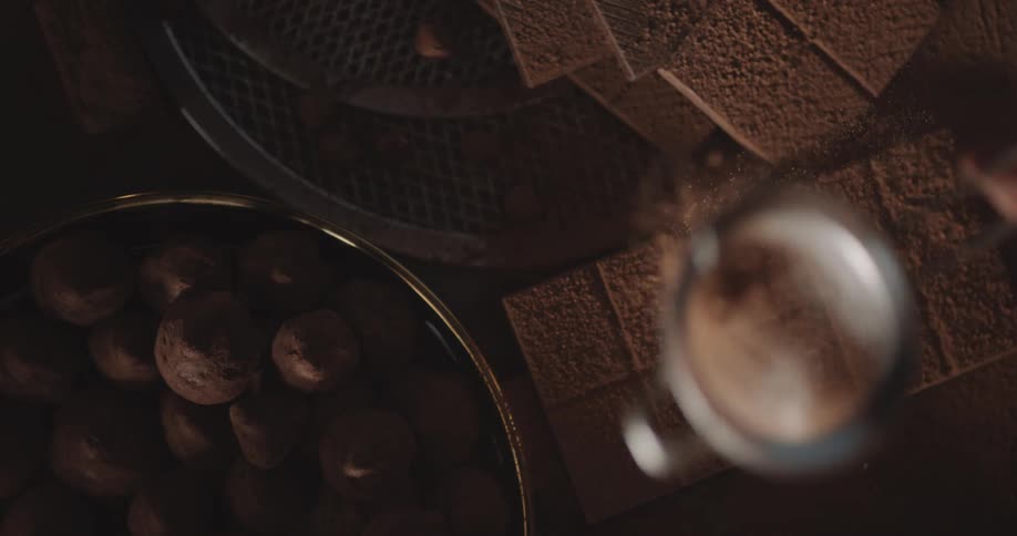 There is chocolate on a table and someone is pouring powder on it