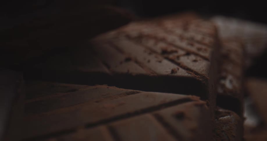 Light shines on square chocolate cookies that are stacked in a pile on a table