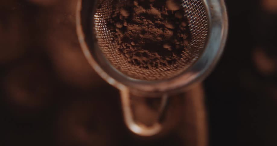 Cocoa powder being sifted through a metal strainer