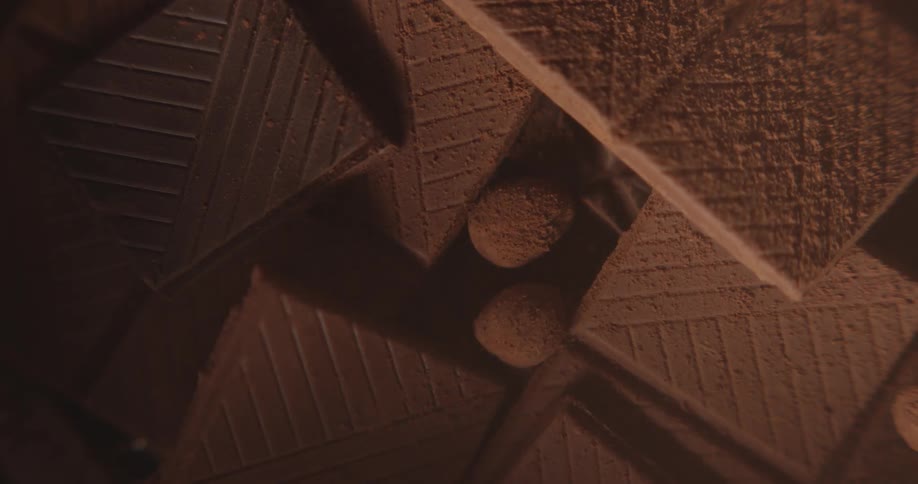 Chocolate tablets broken in squares piled up surrounded by chocolate dust