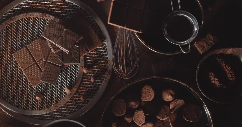 Close up of chocolate bars cookies and whisk on table with chocolate powder