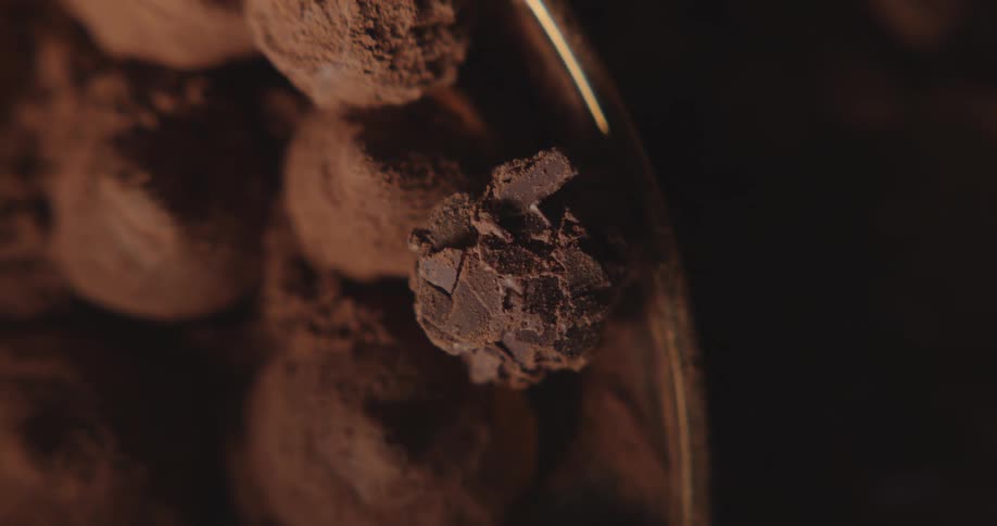 Cocoa covered chocolate truffles sit in metallic gold dish
