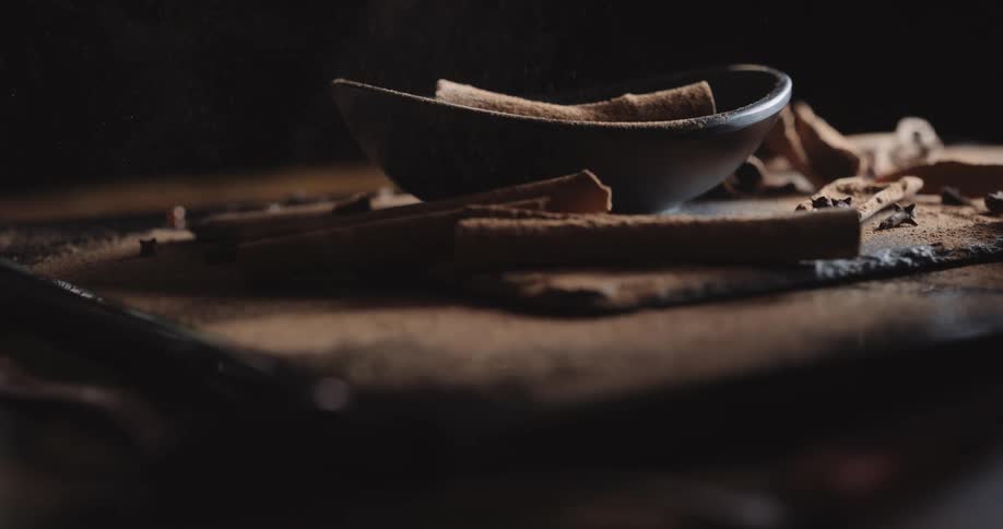 Light shines on a container and chocolate cookies sitting on a table as powder falls from above
