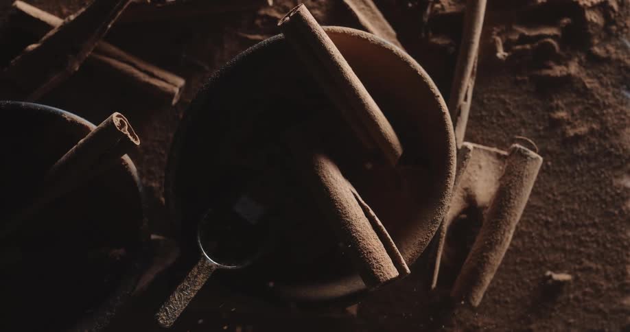 Light shines on a table with cinnamon sticks in a bowl and on the table and the scene goes dark