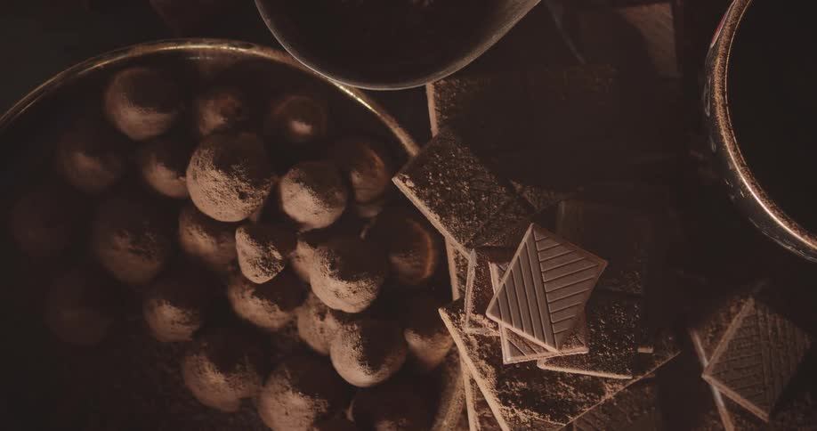 Chocolate tablets broken in squares piled up near a bowl filled with bonbons