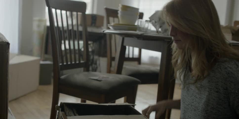 A woman opens a box and pulls a book out of it