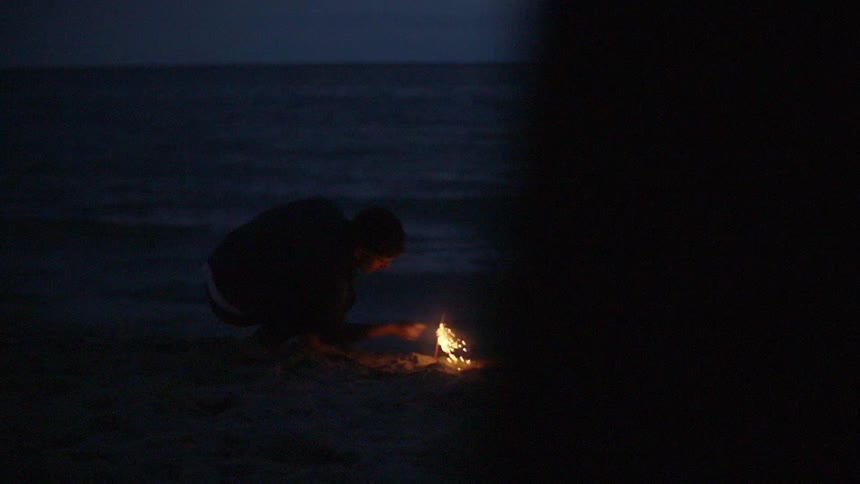 A person lights a firework near a body of water