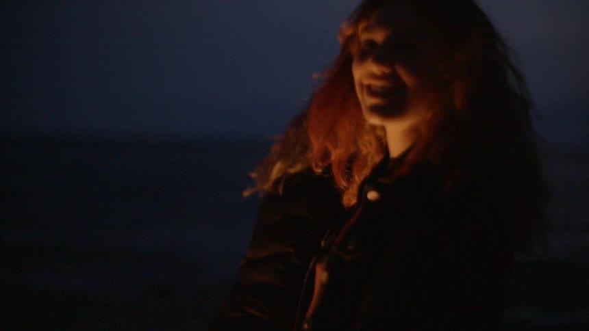 Woman in front of a bonfire on the beach at night