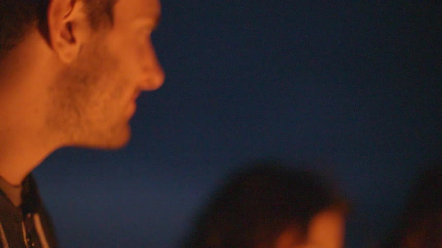 Firelight flickers in a man and woman's faces