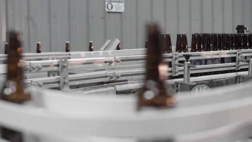 A conveyor belt has bottles moving along it