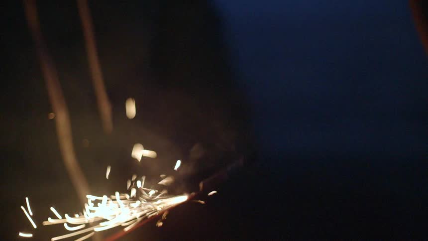 A person lights a firework at night