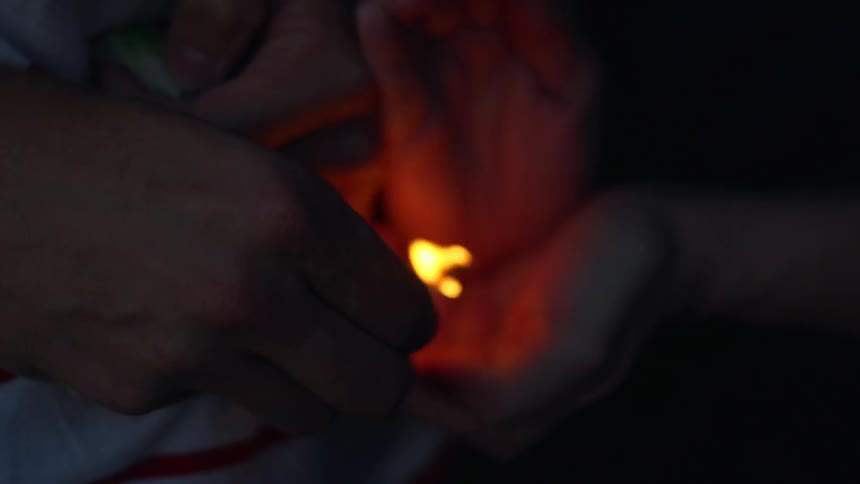 A person holds a lit match near someone else's hand