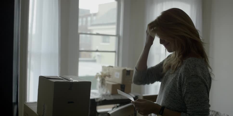 A woman is looking at a piece of paper in a room
