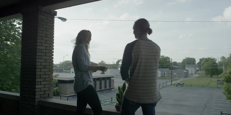 A man and a woman stand on a porch