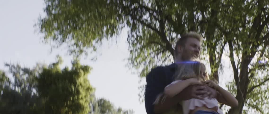 A man picks up his daughter and gleefully spins her around