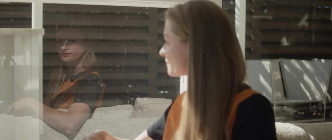Young relaxed woman sitting on a couch at home writes while looking out the window