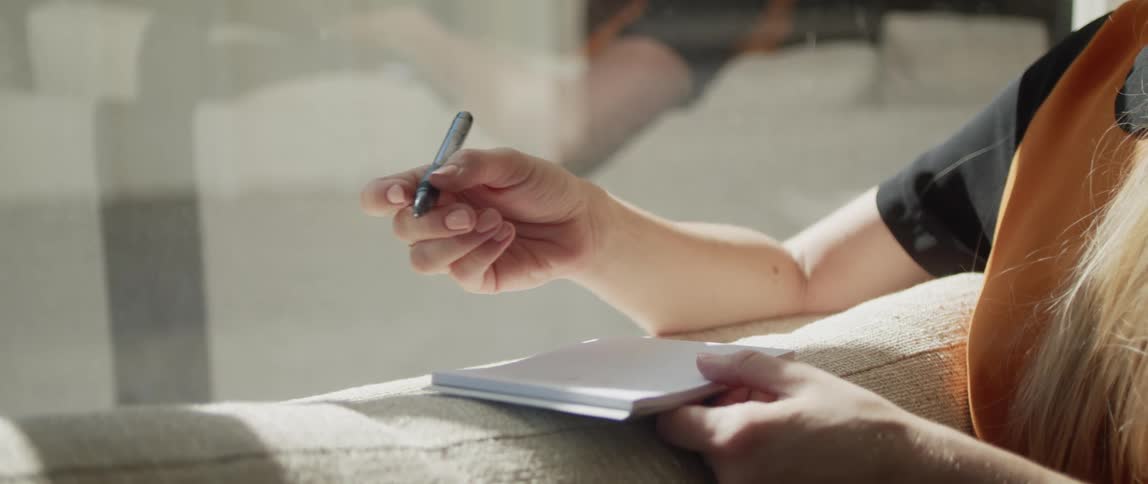 A woman is writing in her pad