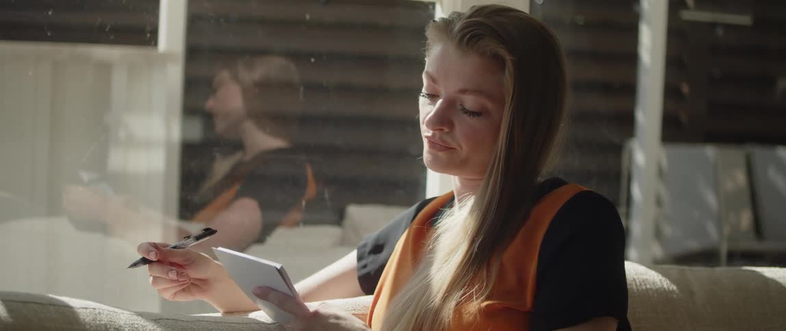Young white women is sitting down and writing something on a piece of paper