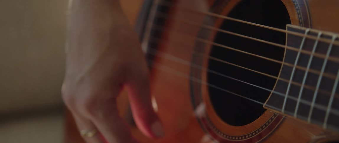 Close up of womans hand playing an acoustic guitar
